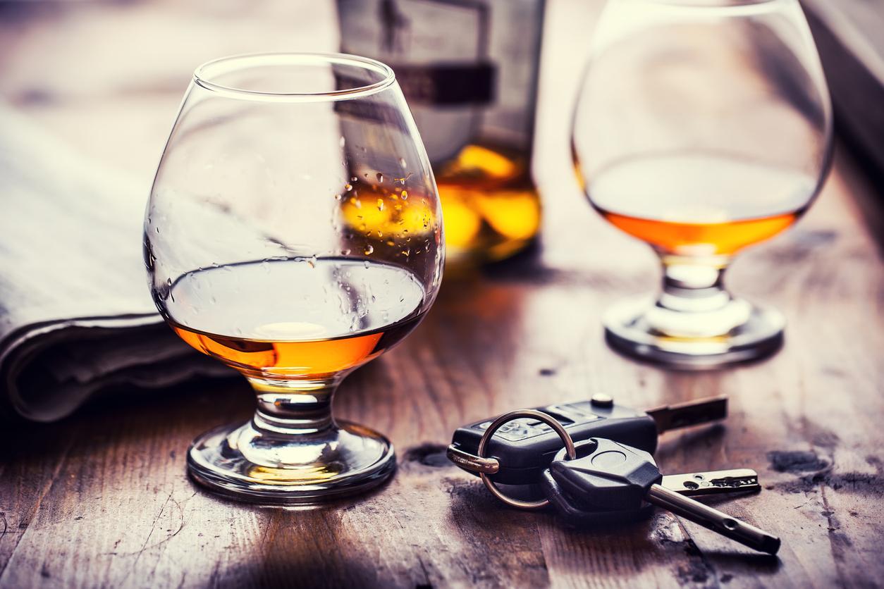 Two glasses of amber alcohol and a pair of car keys setting on a wooden table.
