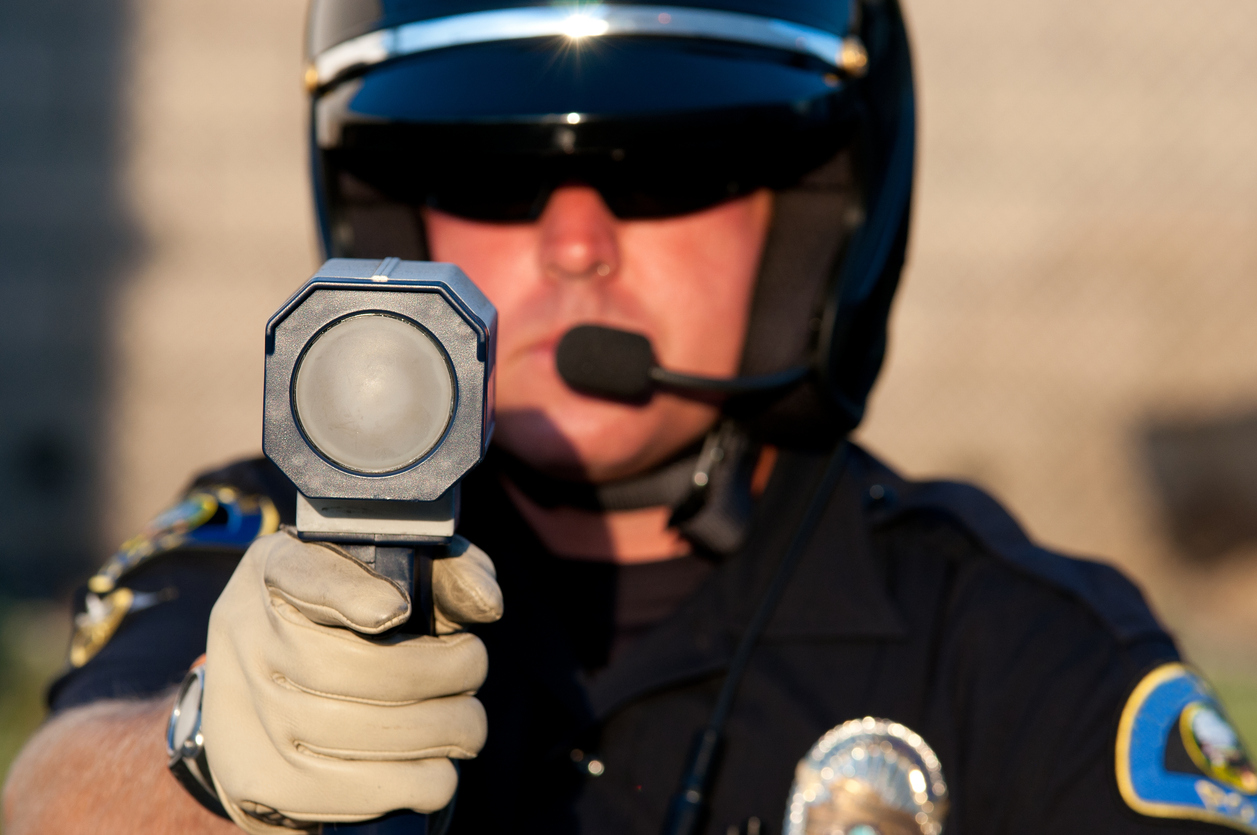 Police officer holding a radar gun to catch drivers speeding